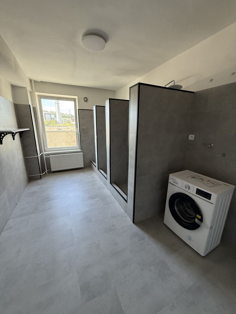 Spoločná kúpeľňa so sprchovacími kútmi a práčkou