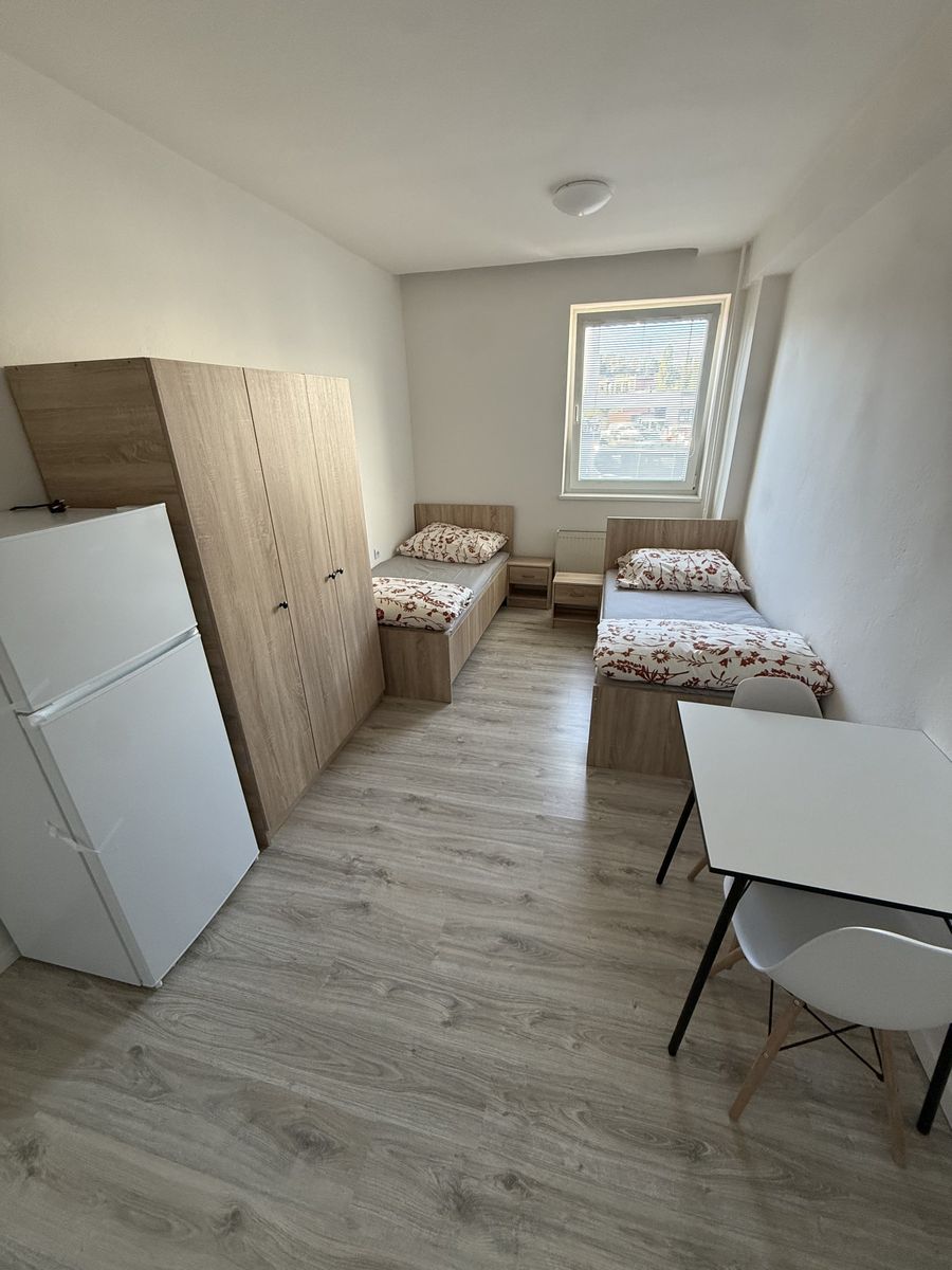 Dvojlôžková izba so skriňou, chladničkou, stolom a dvoma posteľami